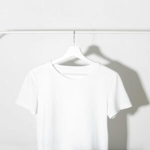 Plain white t-shirt on a hanger against a minimalist white backdrop with shadows.