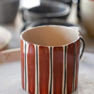 Unique striped ceramic mug in natural lighting, great for kitchen decor.